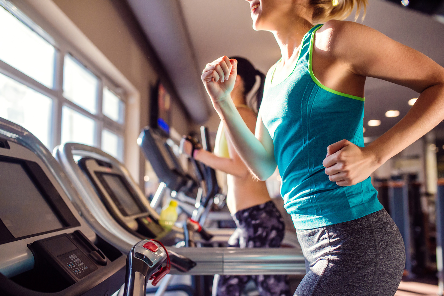 Two Fit Women Running on Treadmills 